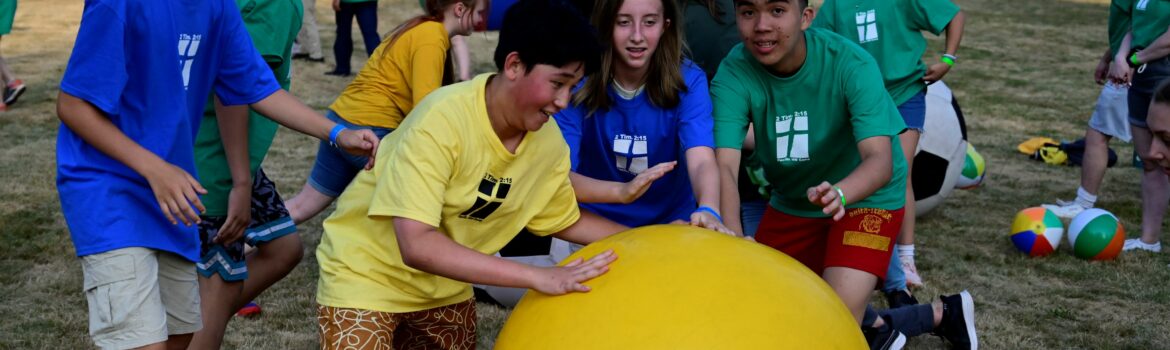 Several campers trying to push a large yellow ball in a game of Organized Chaos